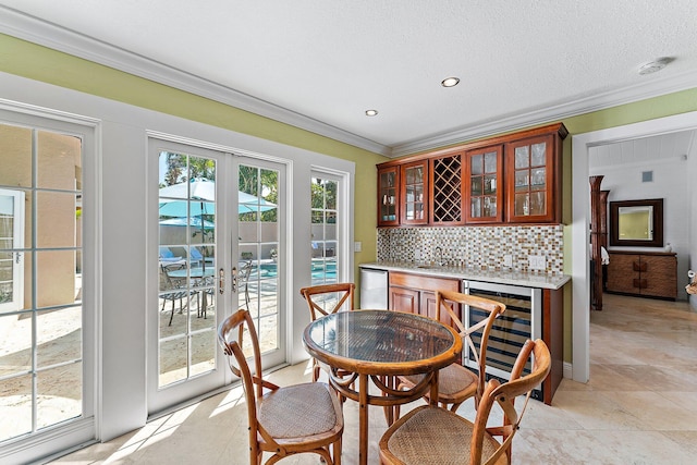 dining space with crown molding, indoor bar, plenty of natural light, and wine cooler