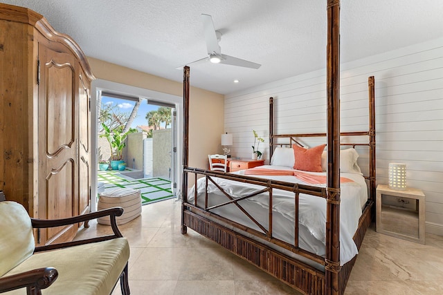 bedroom featuring ceiling fan, wooden walls, access to exterior, and a textured ceiling