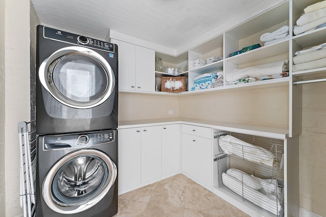 laundry room with cabinets and stacked washing maching and dryer