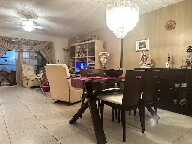 tiled dining area with ceiling fan with notable chandelier and a textured ceiling