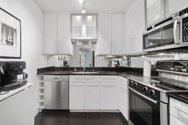 kitchen with appliances with stainless steel finishes, sink, white cabinets, and dark hardwood / wood-style flooring