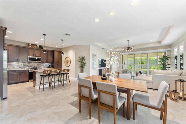 tiled dining area featuring a tray ceiling, a chandelier, and a healthy amount of sunlight