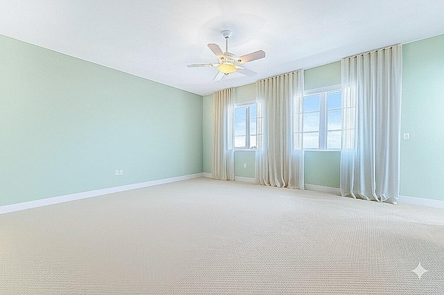 empty room with a ceiling fan, baseboards, and light colored carpet