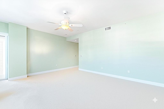 unfurnished room with visible vents, baseboards, light colored carpet, and ceiling fan