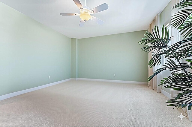 spare room featuring a ceiling fan, baseboards, and light colored carpet