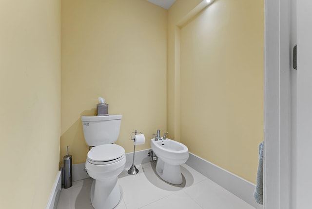half bath featuring a bidet, tile patterned flooring, baseboards, and toilet