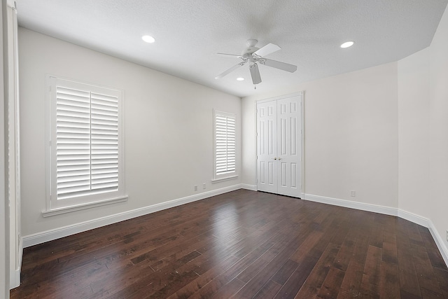 unfurnished bedroom featuring baseboards, dark wood finished floors, a textured ceiling, and recessed lighting