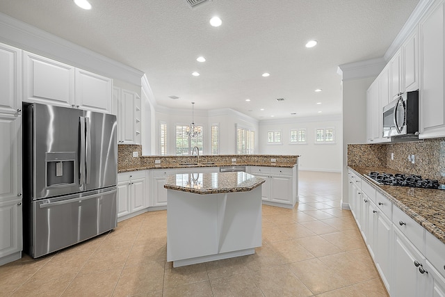 kitchen with stainless steel appliances, light tile patterned flooring, white cabinets, and a center island