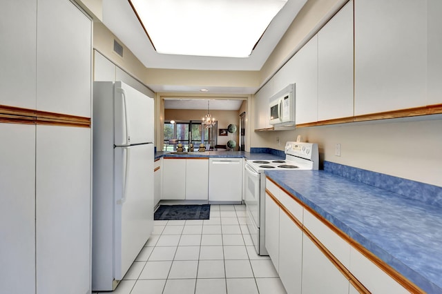 kitchen featuring white cabinetry, a chandelier, light tile patterned floors, and white appliances