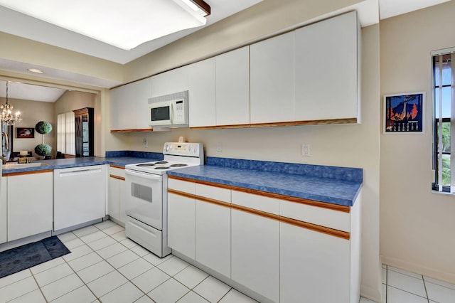 kitchen featuring light tile patterned flooring, sink, white cabinetry, a chandelier, and white appliances