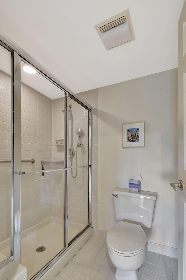 bathroom with tile patterned floors, toilet, and a shower with shower door