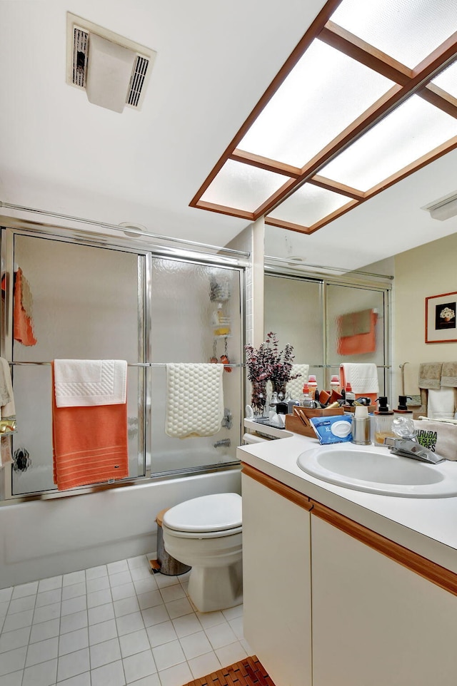 full bathroom with bath / shower combo with glass door, vanity, tile patterned floors, and toilet