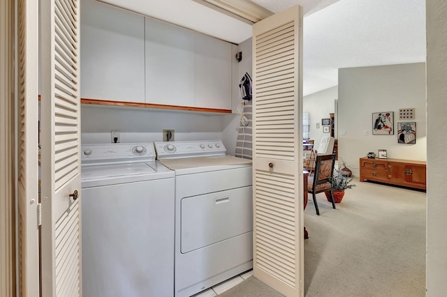 laundry room with light colored carpet, washing machine and dryer, and cabinets