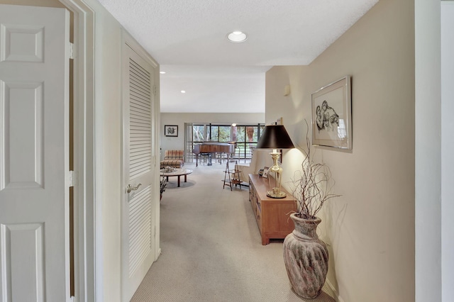 corridor with light carpet and a textured ceiling