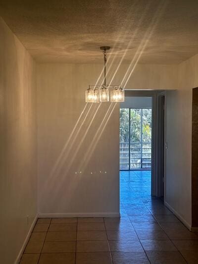 unfurnished dining area featuring baseboards and a chandelier