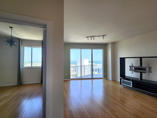 1551 N Flagler Dr Ph L7, West Palm Beach, FL 33401 - unfurnished living room with plenty of natural light, hardwood / wood-style flooring, a chandelier, and baseboards
