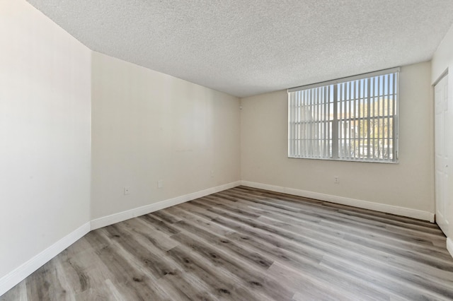 empty room with light hardwood / wood-style flooring and a textured ceiling