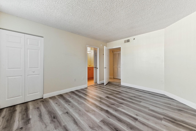 unfurnished bedroom featuring a closet, light hardwood / wood-style floors, and a textured ceiling