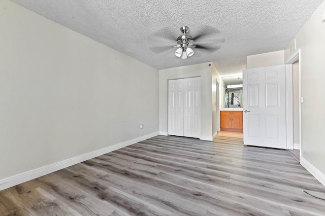 unfurnished bedroom with wood-type flooring, ceiling fan, a textured ceiling, and a closet