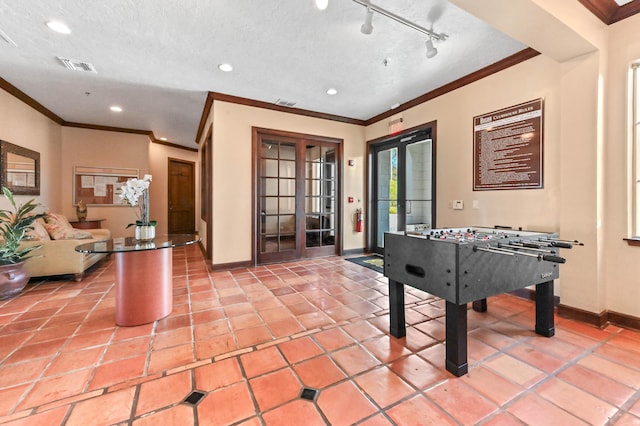 recreation room featuring light tile patterned floors, track lighting, ornamental molding, a textured ceiling, and french doors