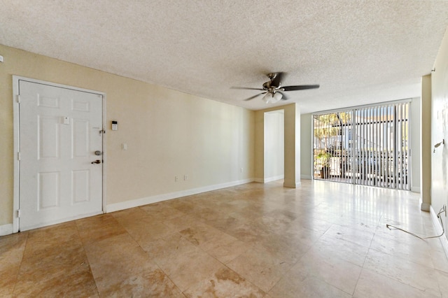 spare room with a textured ceiling, expansive windows, and ceiling fan