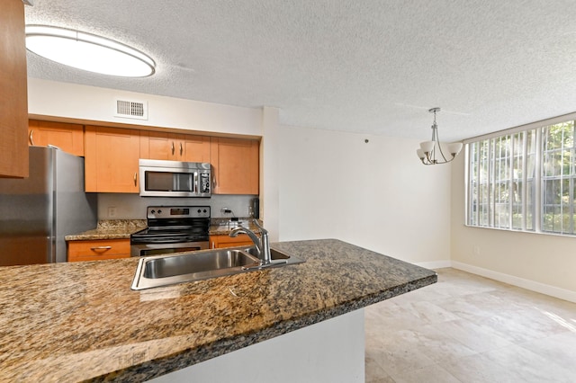 kitchen featuring sink, hanging light fixtures, stainless steel appliances, and dark stone counters