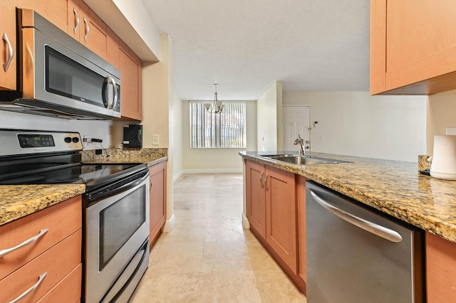 kitchen with appliances with stainless steel finishes, sink, hanging light fixtures, light tile patterned floors, and light stone counters