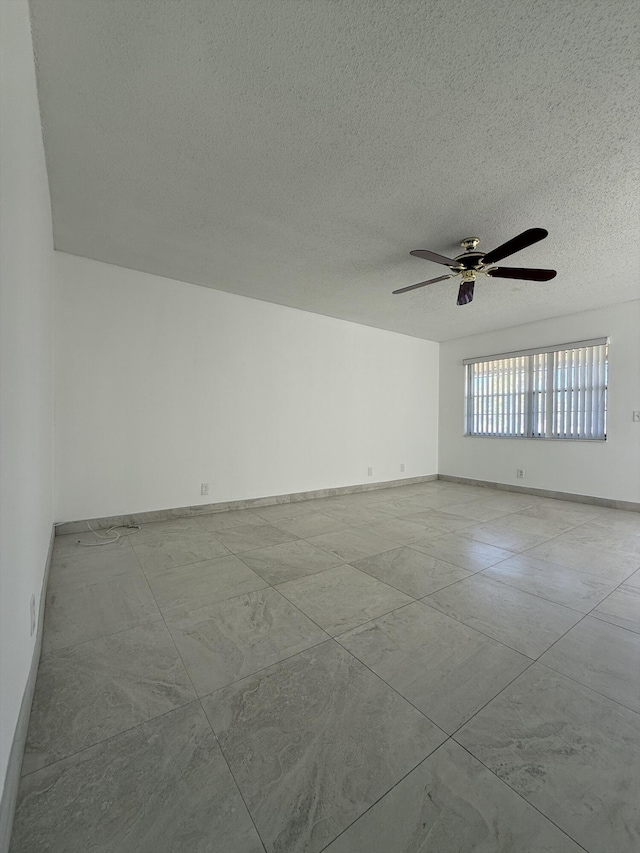 empty room featuring ceiling fan and a textured ceiling