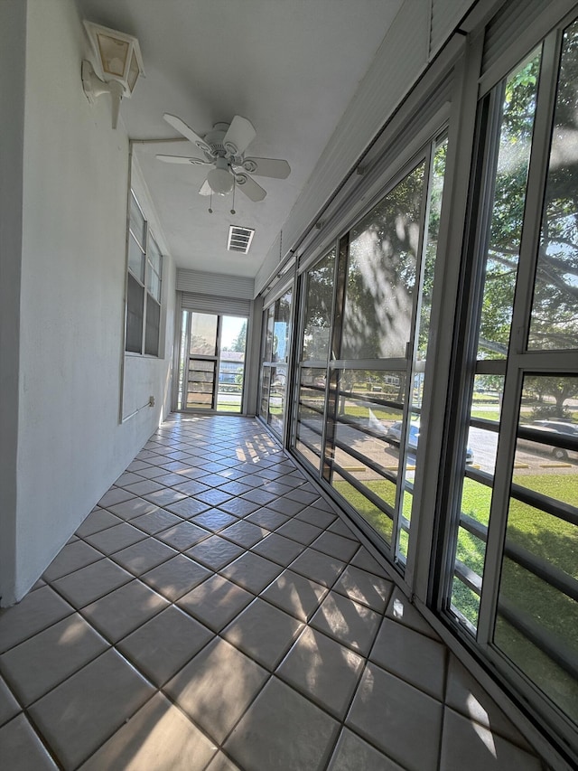 unfurnished sunroom with ceiling fan