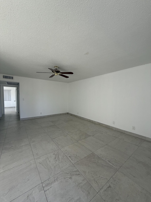 empty room with ceiling fan and a textured ceiling