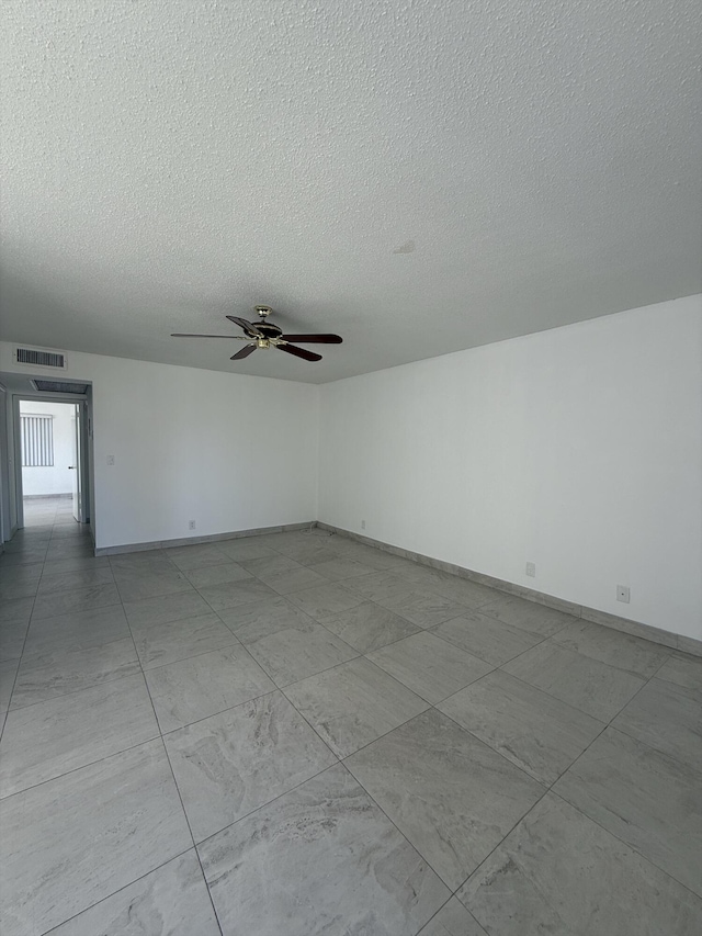 empty room with ceiling fan and a textured ceiling