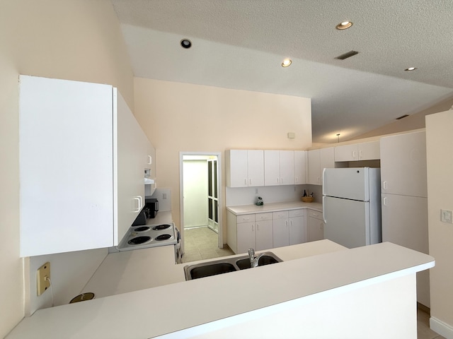 kitchen with white refrigerator, white cabinetry, sink, and kitchen peninsula