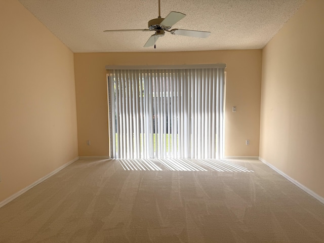 empty room with ceiling fan, light colored carpet, and a textured ceiling