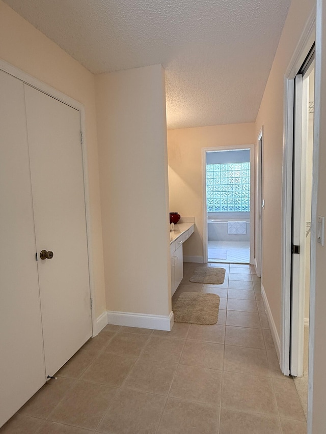 hallway with light tile patterned floors and a textured ceiling