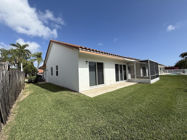 rear view of property featuring cooling unit, a yard, a sunroom, and a patio