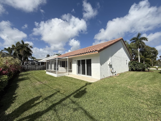 back of house with a patio area, a sunroom, and a lawn