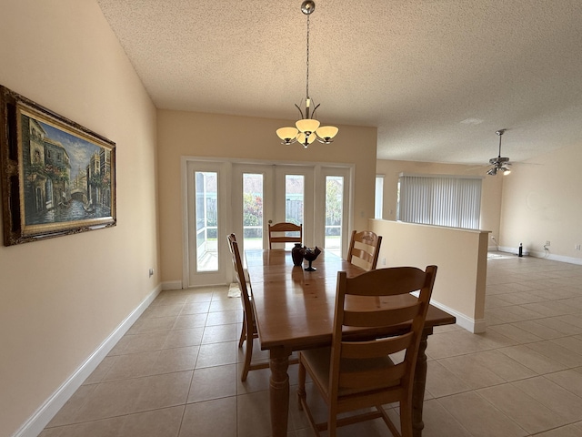 tiled dining room featuring ceiling fan with notable chandelier and a textured ceiling