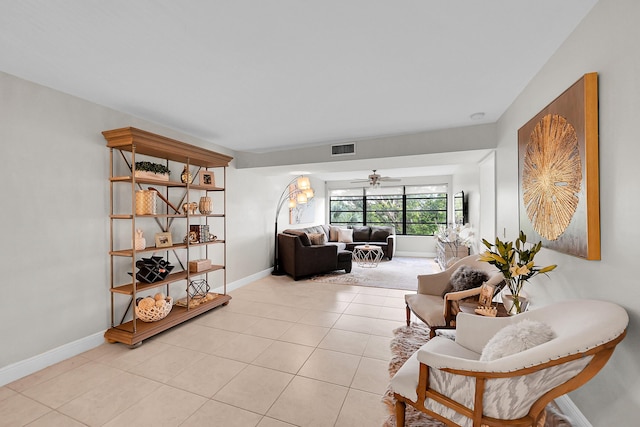 living area featuring light tile patterned floors, baseboards, visible vents, and ceiling fan