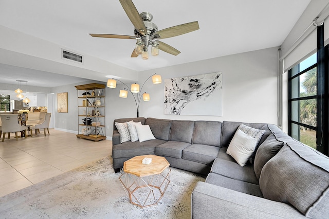 tiled living area with baseboards, visible vents, and a ceiling fan