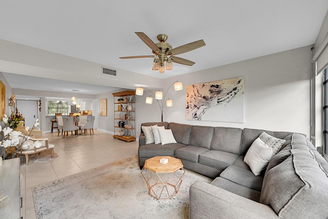 tiled living area featuring a ceiling fan, visible vents, and baseboards