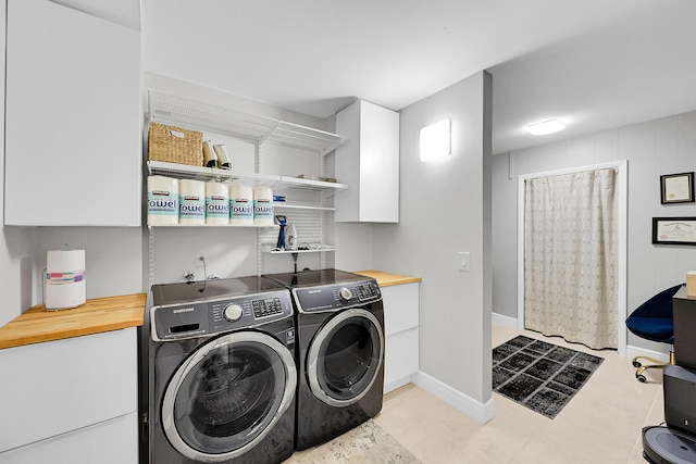 washroom featuring cabinet space, washing machine and dryer, and baseboards