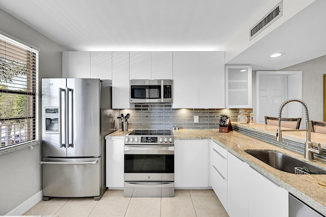 kitchen with light tile patterned floors, stainless steel appliances, a sink, visible vents, and tasteful backsplash