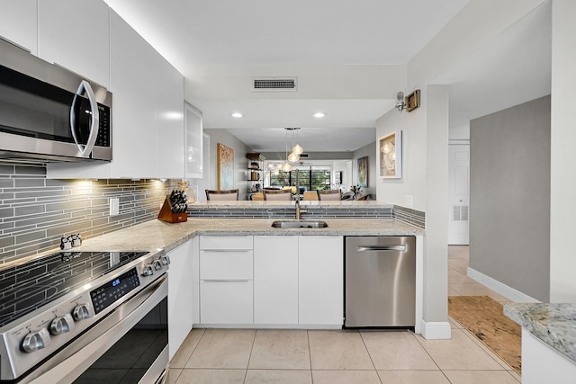 kitchen featuring light tile patterned floors, a sink, visible vents, appliances with stainless steel finishes, and decorative backsplash