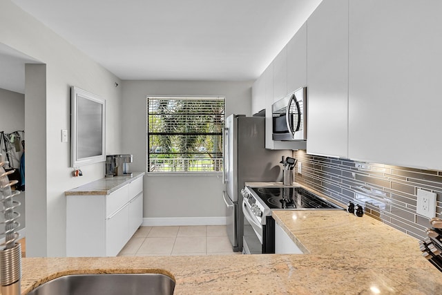 kitchen featuring light tile patterned floors, appliances with stainless steel finishes, backsplash, and white cabinetry