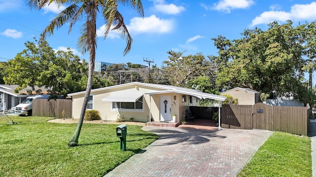 view of front of property featuring decorative driveway, a gate, stucco siding, a carport, and a front lawn