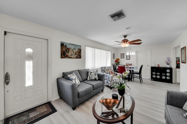 living room with light wood-type flooring, visible vents, and a ceiling fan