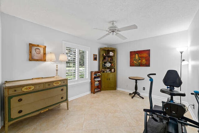 workout area with ceiling fan, light tile patterned floors, and a textured ceiling