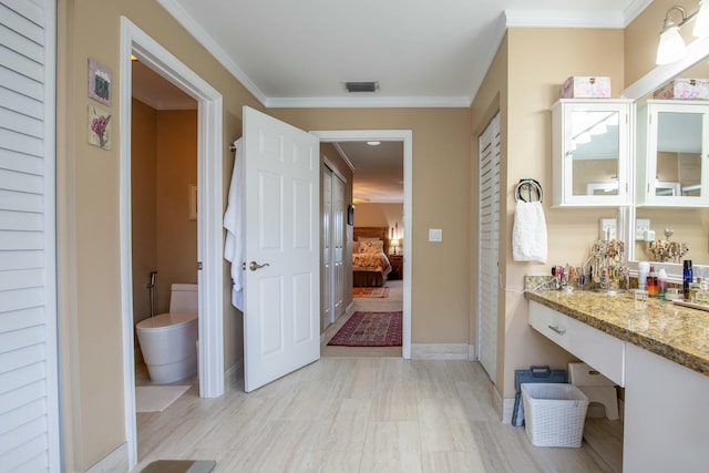 bathroom with vanity, crown molding, and toilet