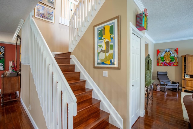 stairs with hardwood / wood-style flooring, ornamental molding, and a textured ceiling