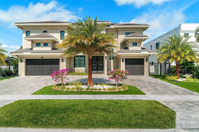 view of front facade featuring a garage, fence, french doors, decorative driveway, and stucco siding